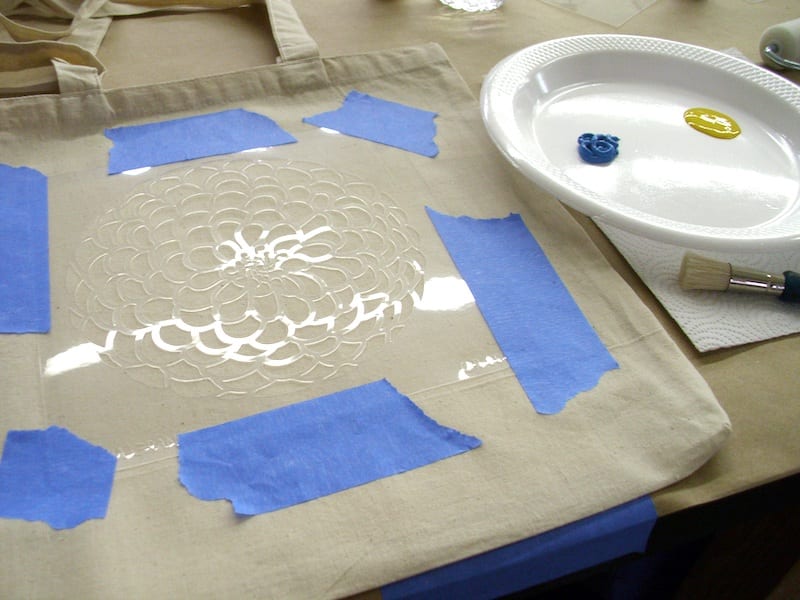 use painters tape to attach stencil to tote bag