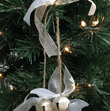 a rustic jingle bell ornament hanging on a tree