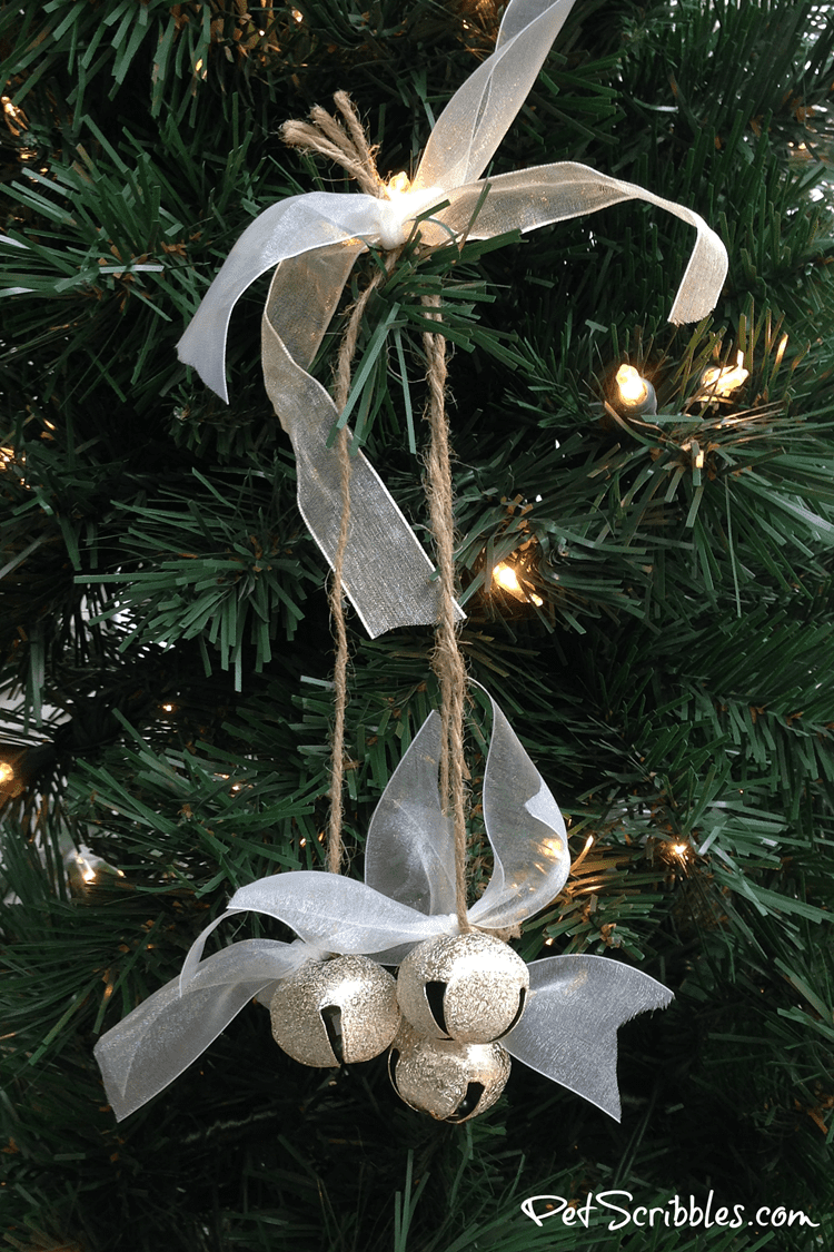 a rustic jingle bell ornament hanging on a tree