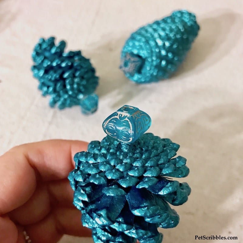 adding a bead for hanging to a pinecone ornament