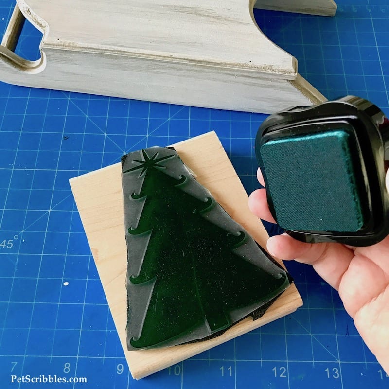 using a Christmas tree stamp on a rustic wood sled