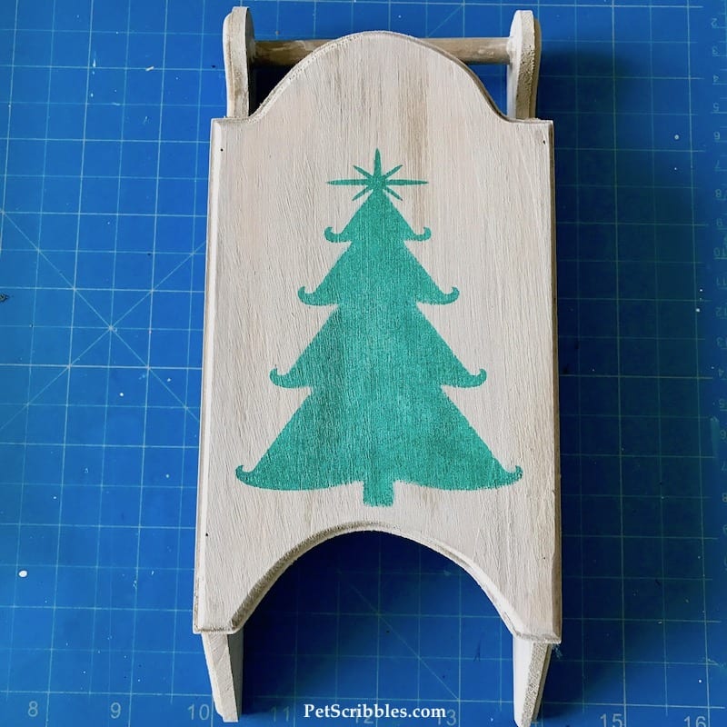 stamped image of green Christmas tree on wood sled