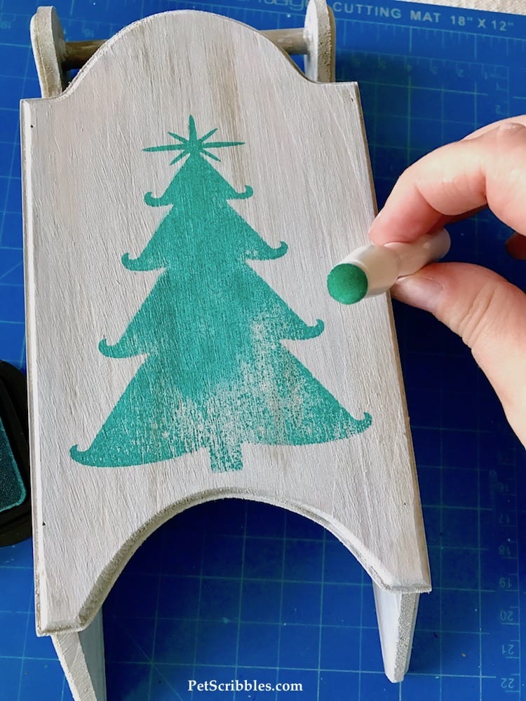 using a Christmas tree stamp on a rustic wood sled