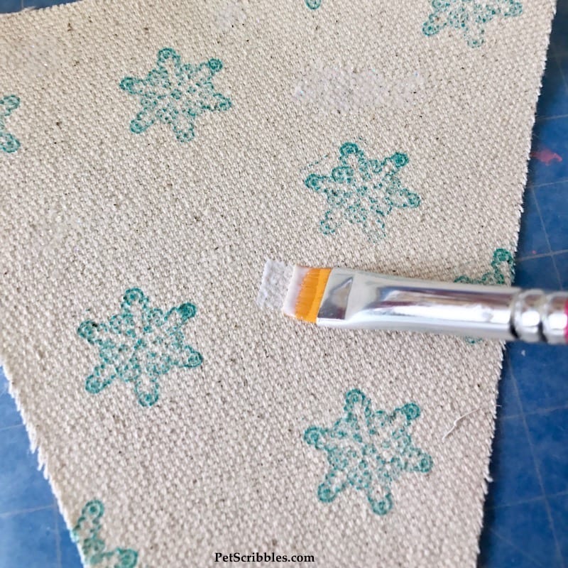 applying sparkle Mod Podge to canvas fabric