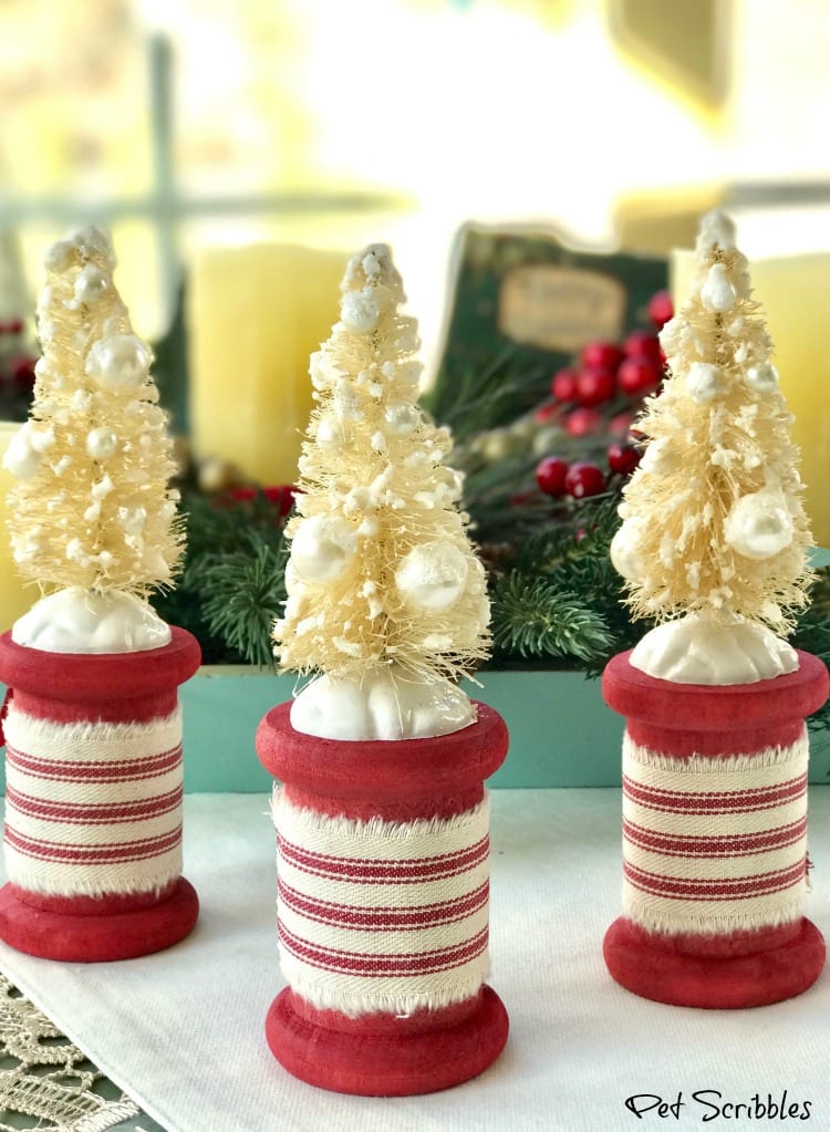 trio of red spools with ivory bottle brush trees attached to them