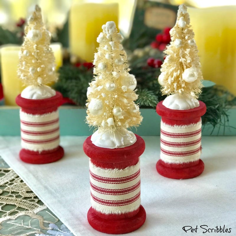 farmhouse ticking fabric wrapped around red spools with ivory bottle brush trees