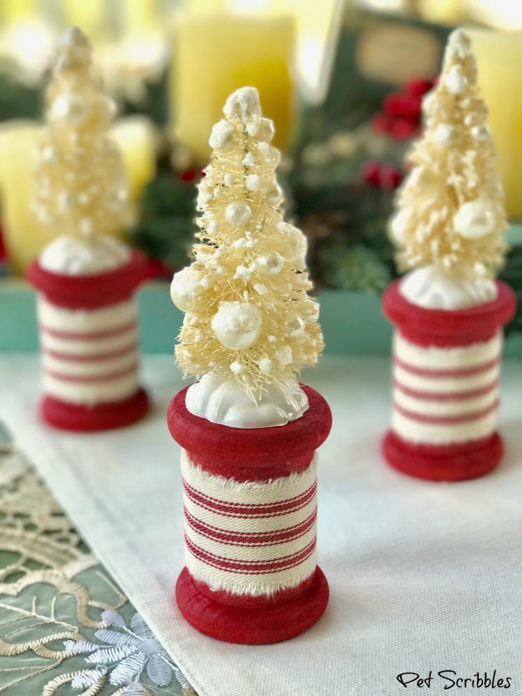 Ivory bottle brush trees attached to red spools wrapped in red/ivory fabric