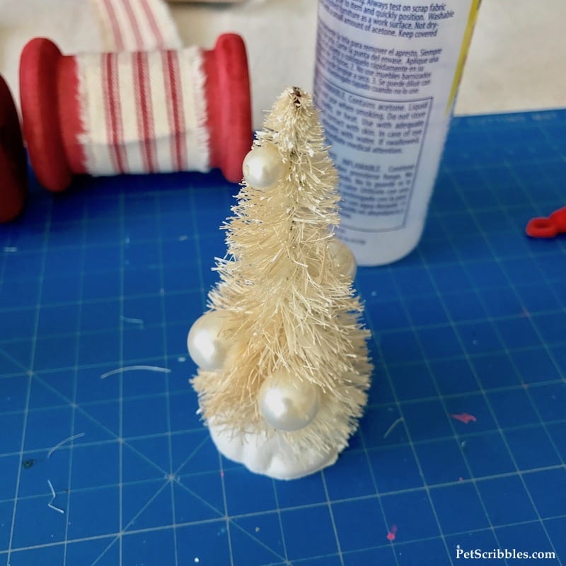 adding tiny ornaments to a bottle brush tree