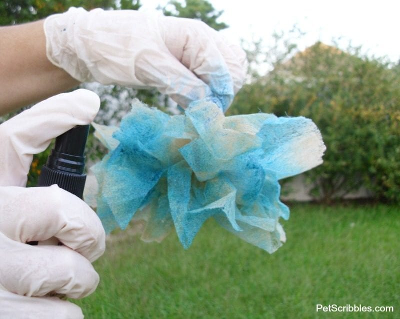 spraying teal glimmer mist on dryer sheets