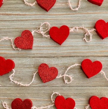 felt heart garland laying on rustic pale wood background