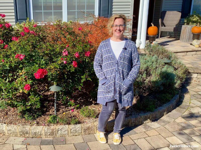 woman smiling in front of a home's foundation garden bed in Fall